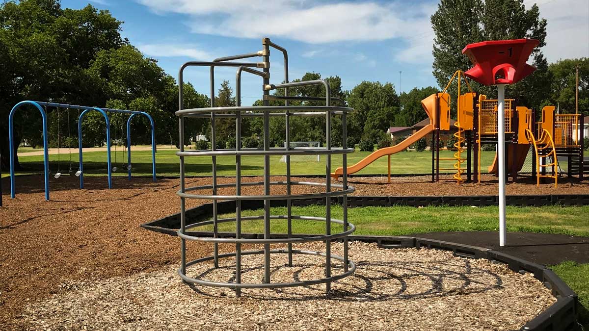 Park with swings, climbing structure and a yellow playground. Playground company Fargo, North Dakota playground installation playground equipment slides swings surfacing climbers children recreation safety durable
